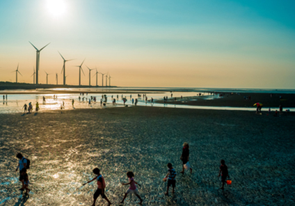 Wind farm on a beach with lots of visitors